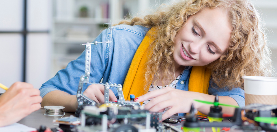 Confident high school student concentrates while building a robotic vehicle.